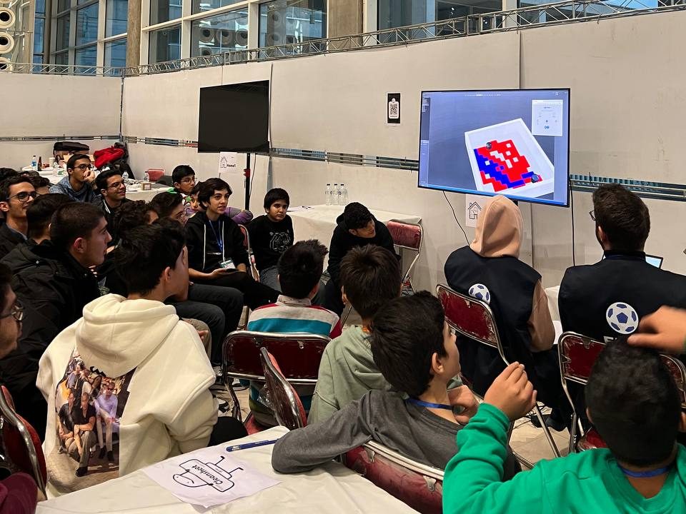 Students at a Smart Home League event watching a robot match on screen